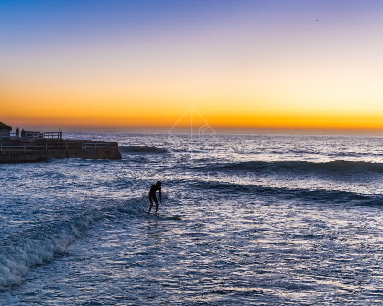 The beach, the surf and the pier in Ocean Beach, with surfers out.