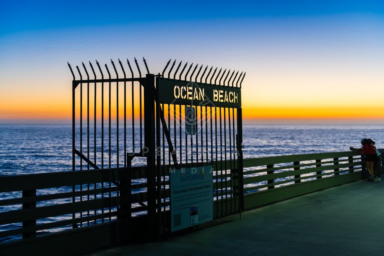 The beach, the pier and the ocean in Ocean Beach, with people walking.