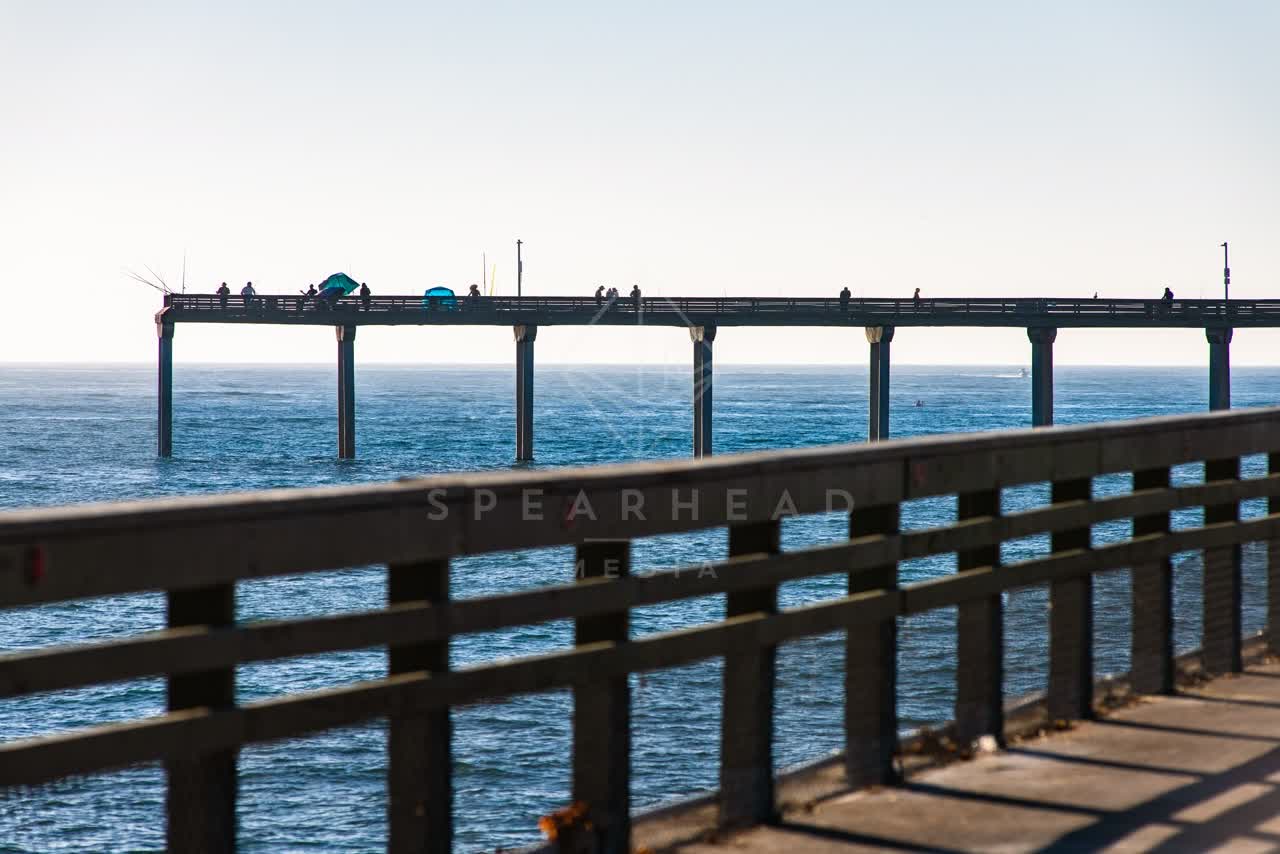 The beach, the pier and the ocean in Ocean Beach, with people walking.