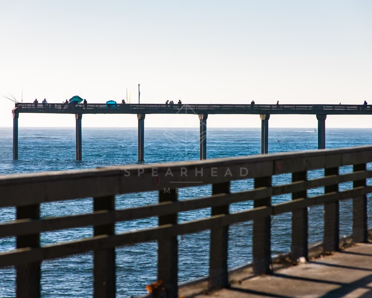 The beach, the pier and the ocean in Ocean Beach, with people walking.