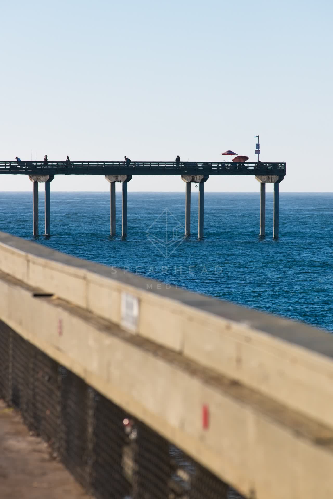 The beach, the pier and the ocean in Ocean Beach, with people walking.