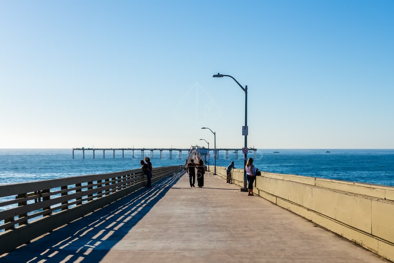 The beach, the pier and the ocean in Ocean Beach, with people walking.