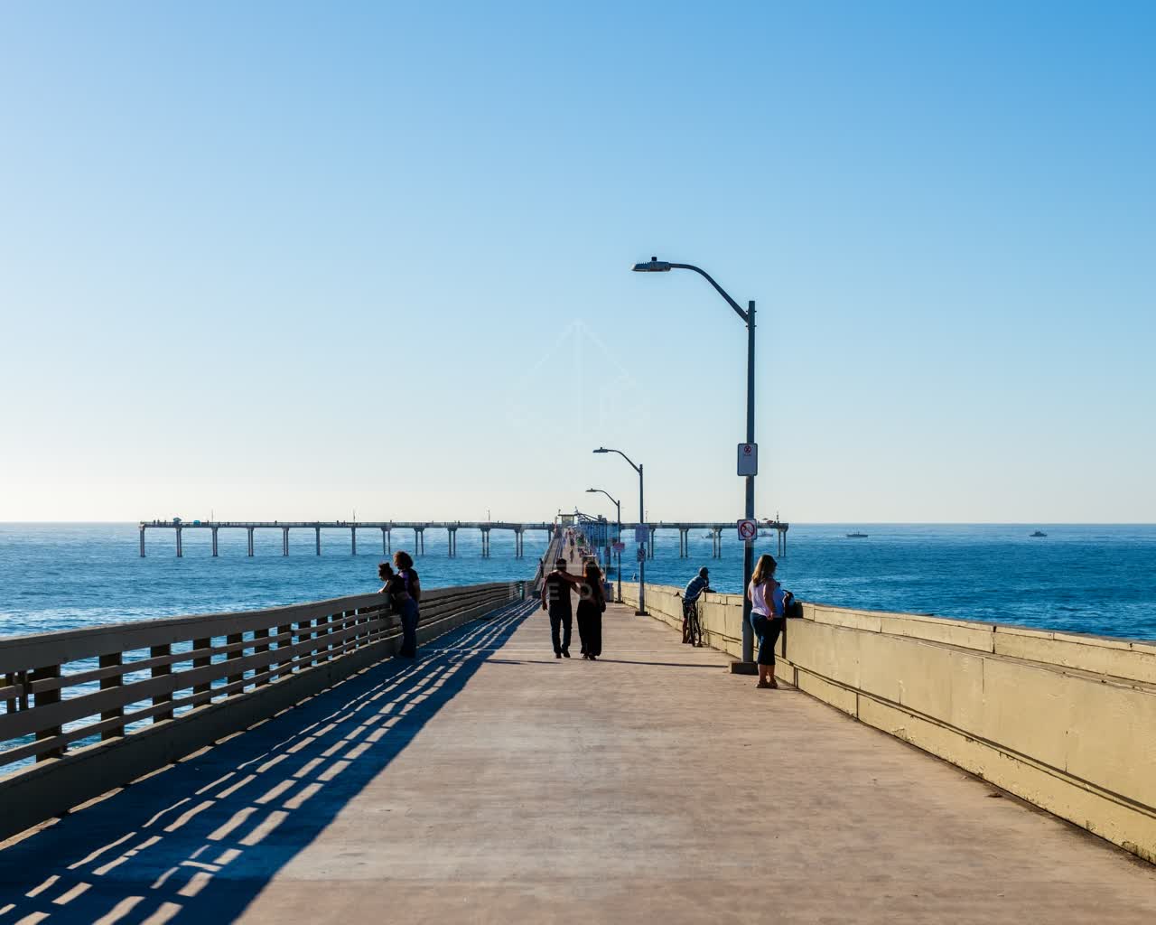 The beach, the pier and the ocean in Ocean Beach, with people walking.