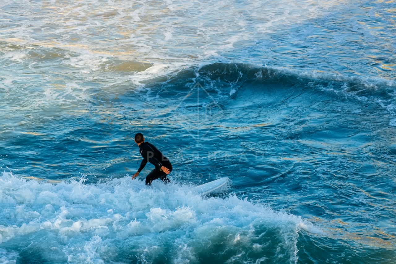 Elevated view of the beach, the surf and the ocean in Ocean Beach, with surfers out.