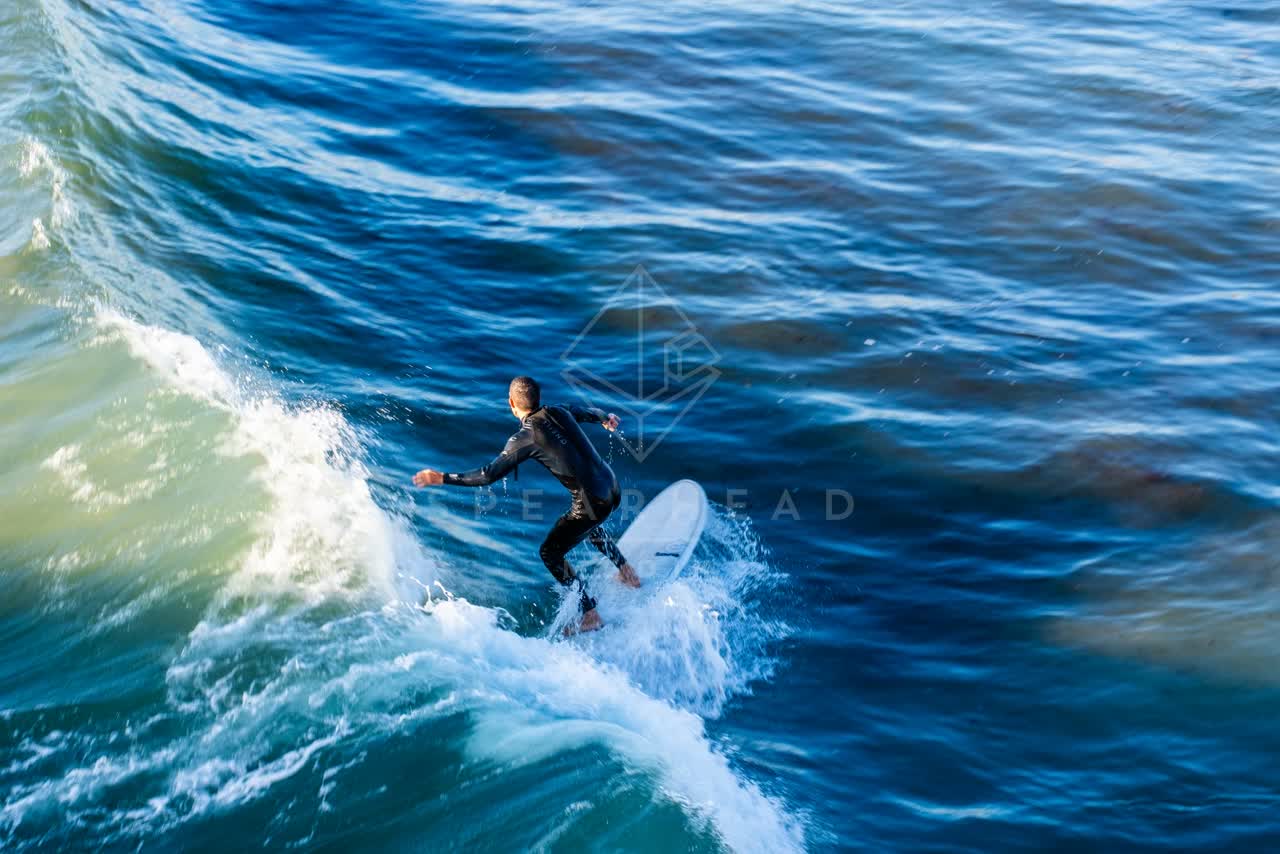 Low aerial view of the beach, the surf and the ocean in Ocean Beach, with surfers out.