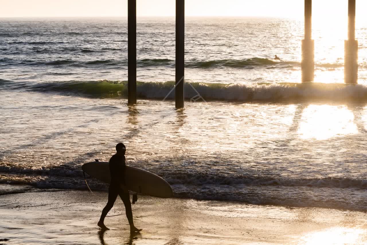 The beach, the surf and the pier in Ocean Beach, with people walking.