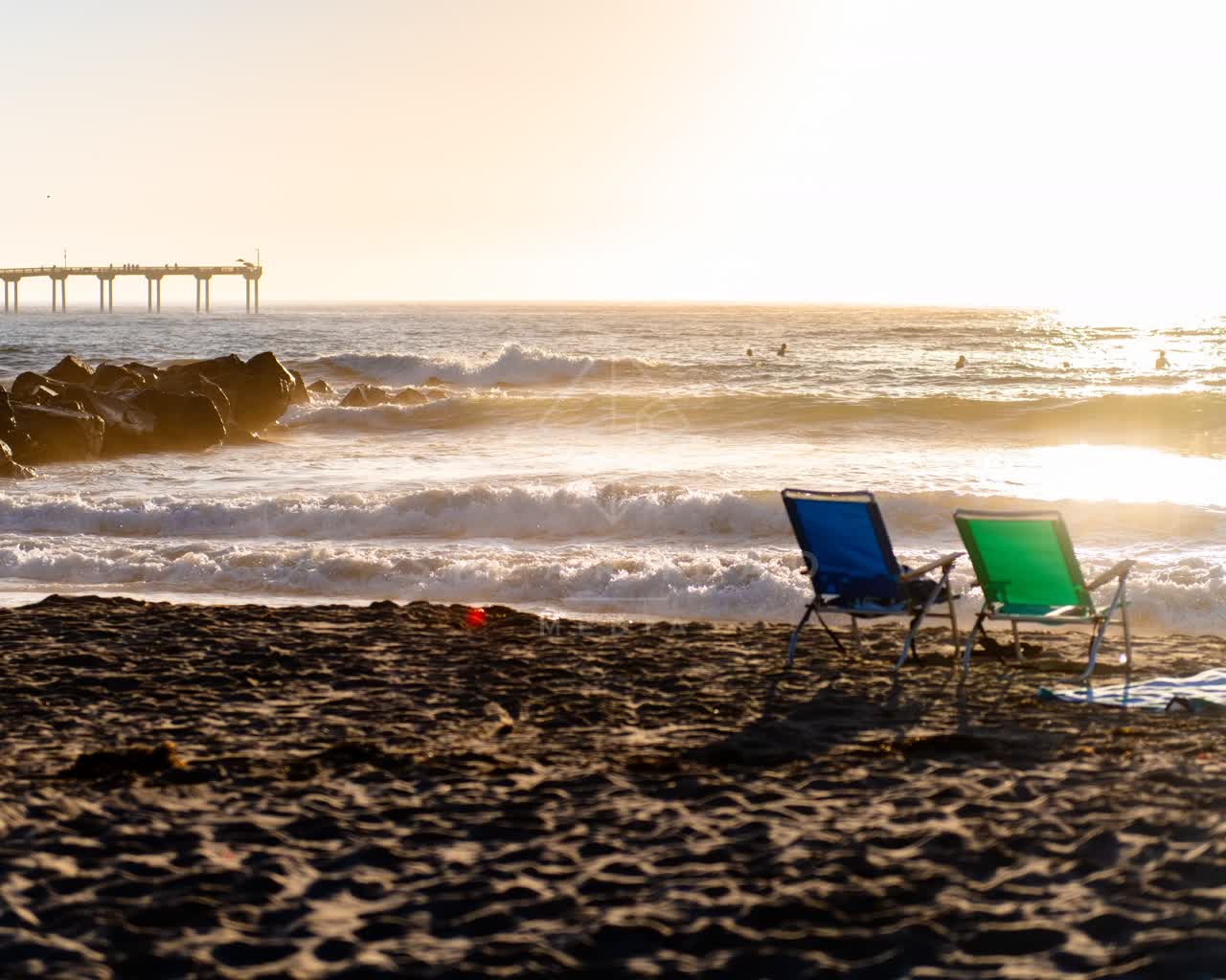 The beach, the surf and the pier in Ocean Beach, with surfers out.