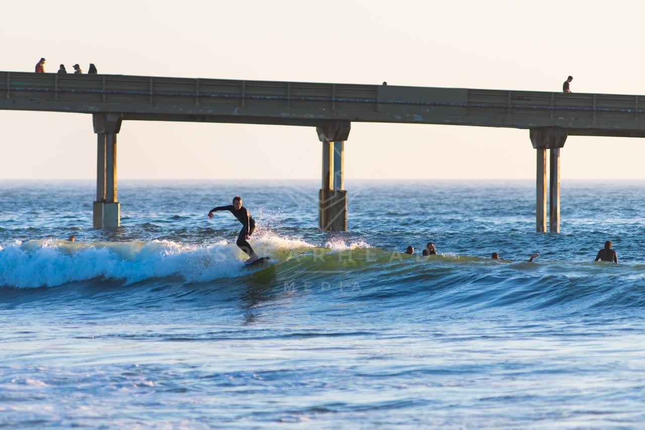 View from the water of the beach, the surf and the pier in Ocean Beach, with surfers out.