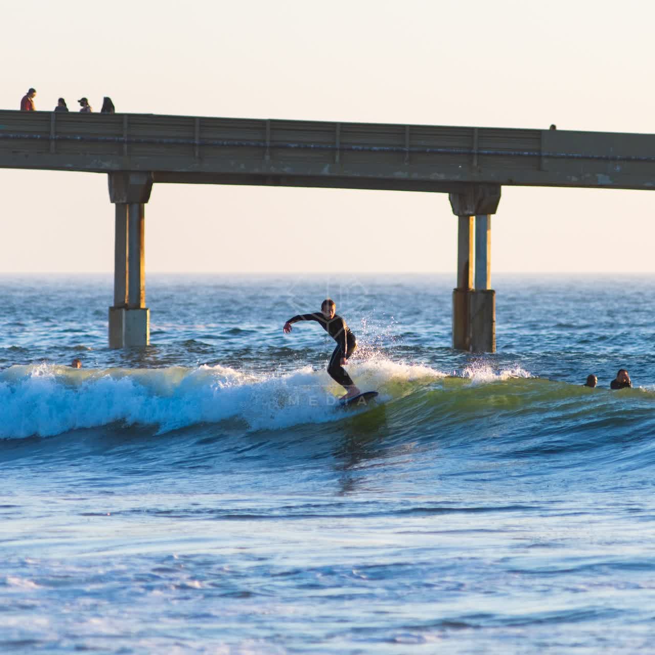 View from the water of the beach, the surf and the pier in Ocean Beach, with surfers out.