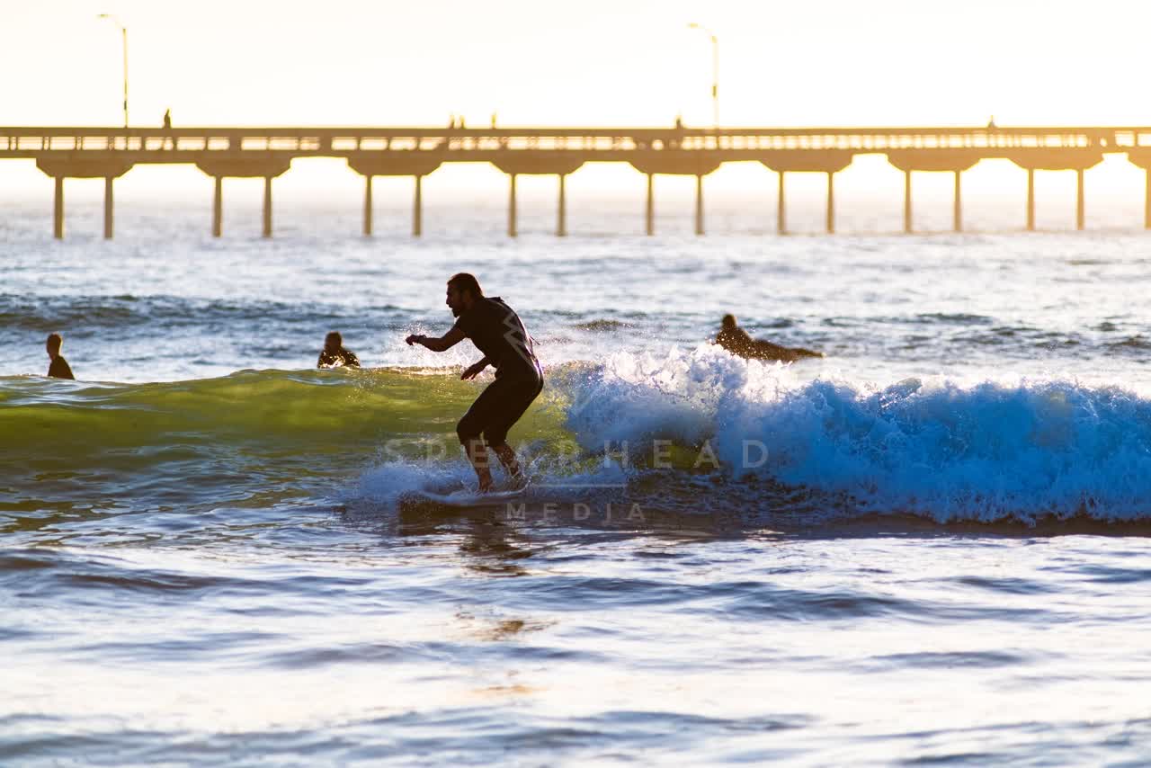View from the water of the beach, the surf and the pier in Ocean Beach, with surfers out.