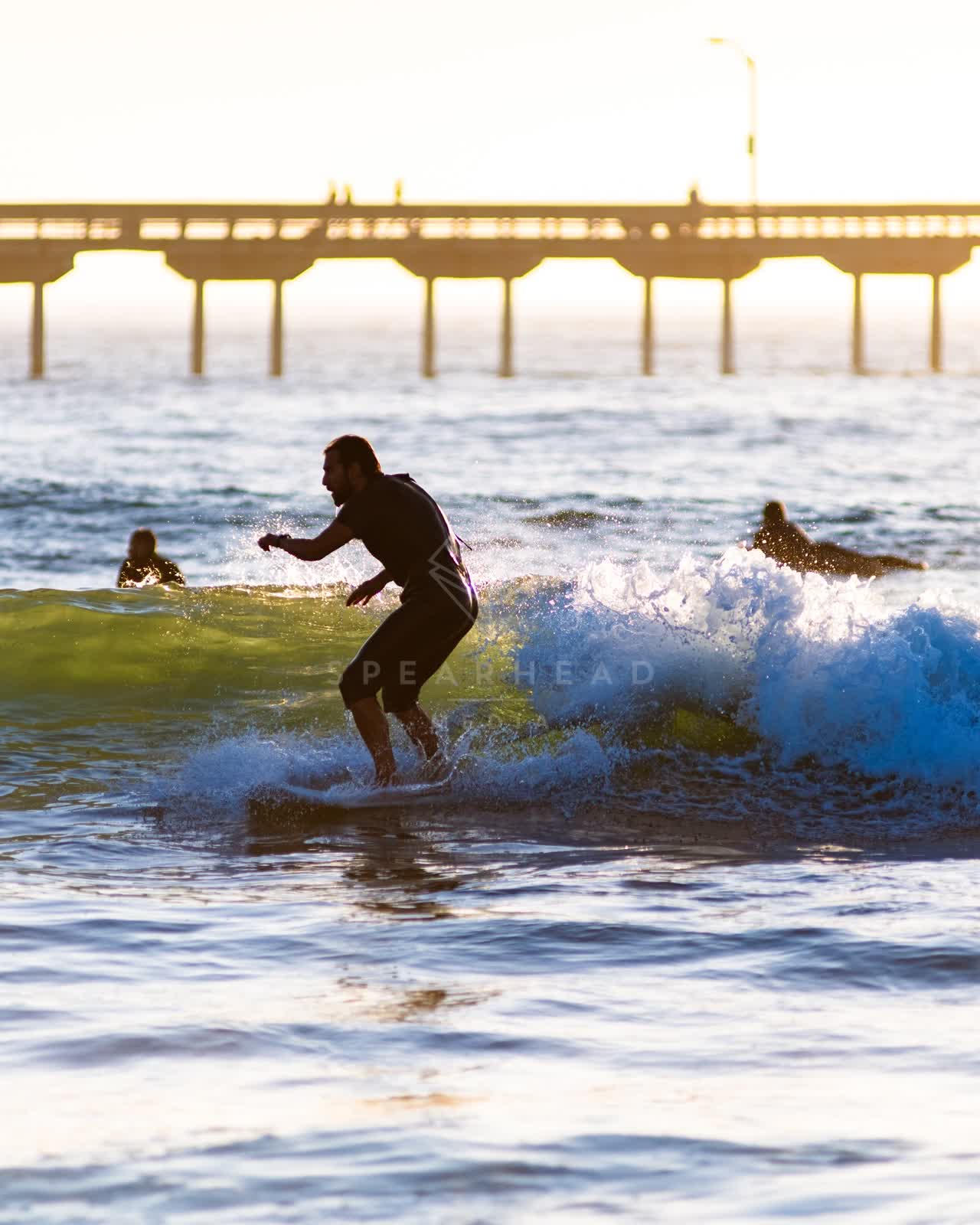 View from the water of the beach, the surf and the pier in Ocean Beach, with surfers out.