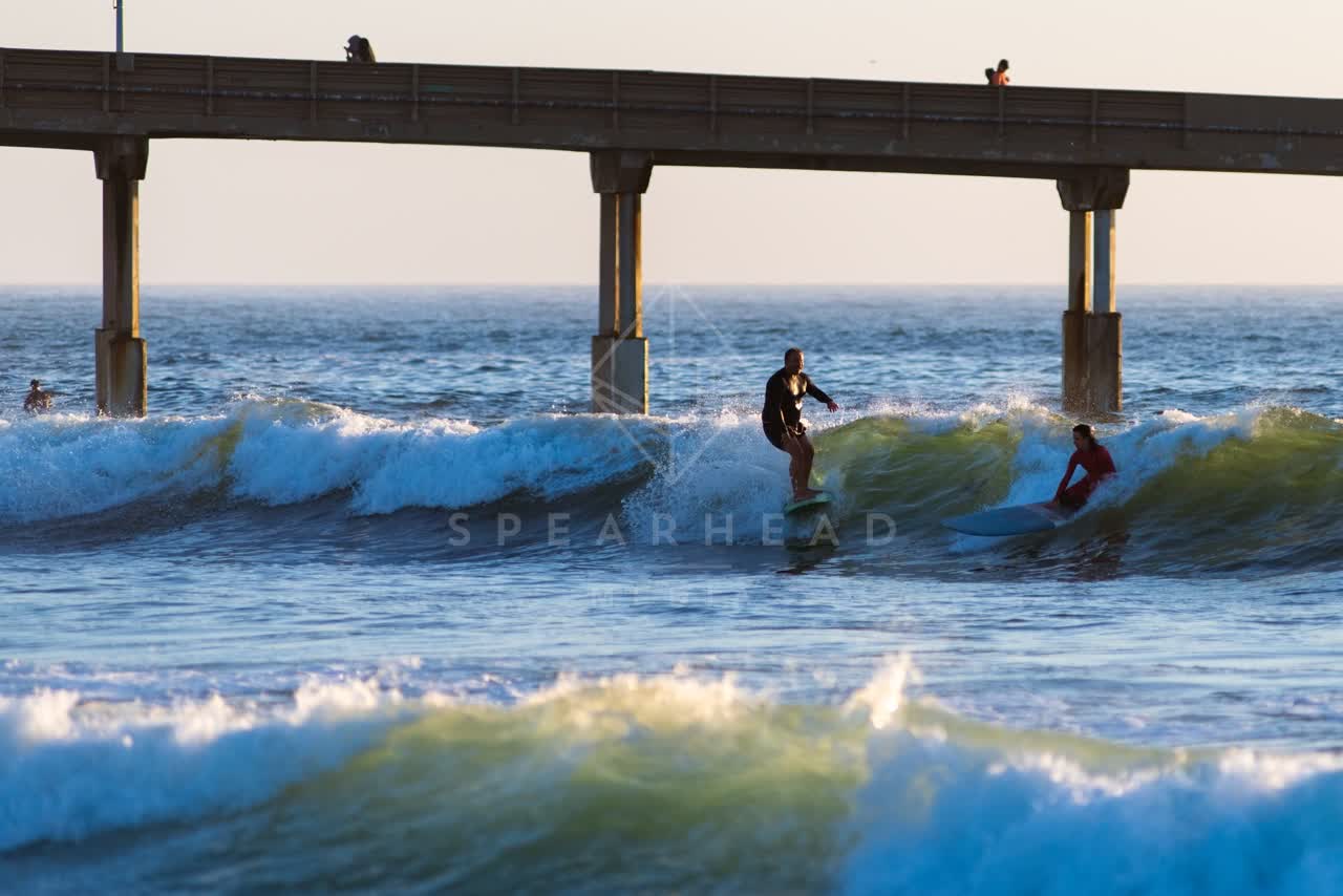 View from the water of the beach, the surf and the pier in Ocean Beach, with surfers out.