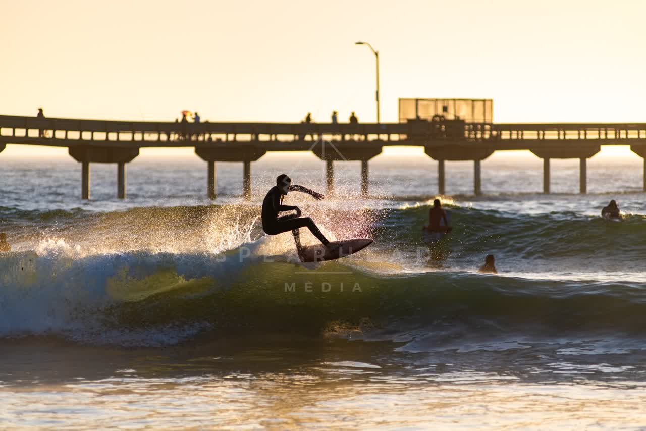 View from the water of the beach, the surf and the pier in Ocean Beach, with surfers out.