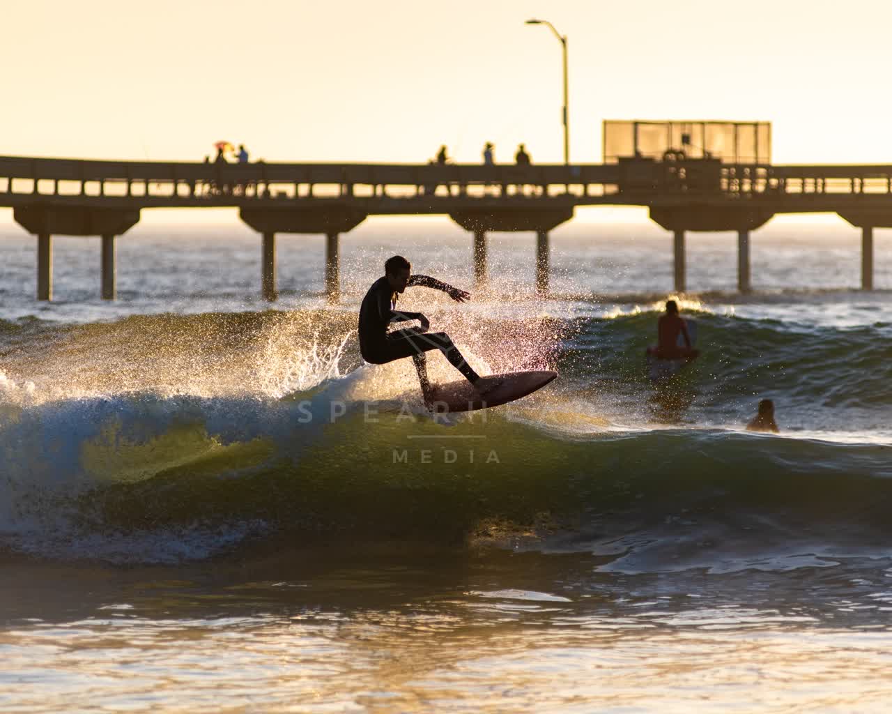 View from the water of the beach, the surf and the pier in Ocean Beach, with surfers out.