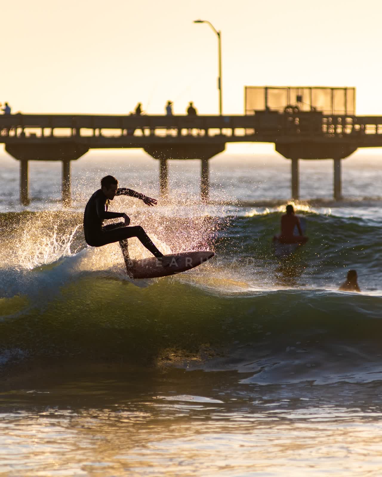 View from the water of the beach, the surf and the pier in Ocean Beach, with surfers out.