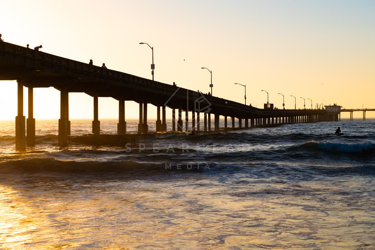 View from the water of the beach, the surf and the pier in Ocean Beach, with surfers out.