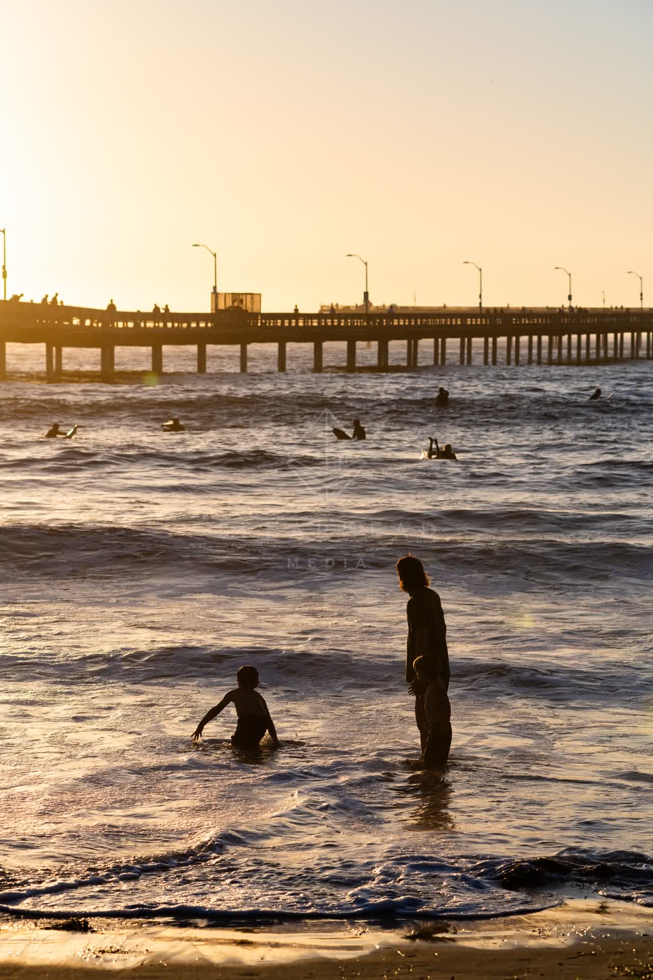 View from the water of the beach, the surf and the pier in Ocean Beach, with surfers out.
