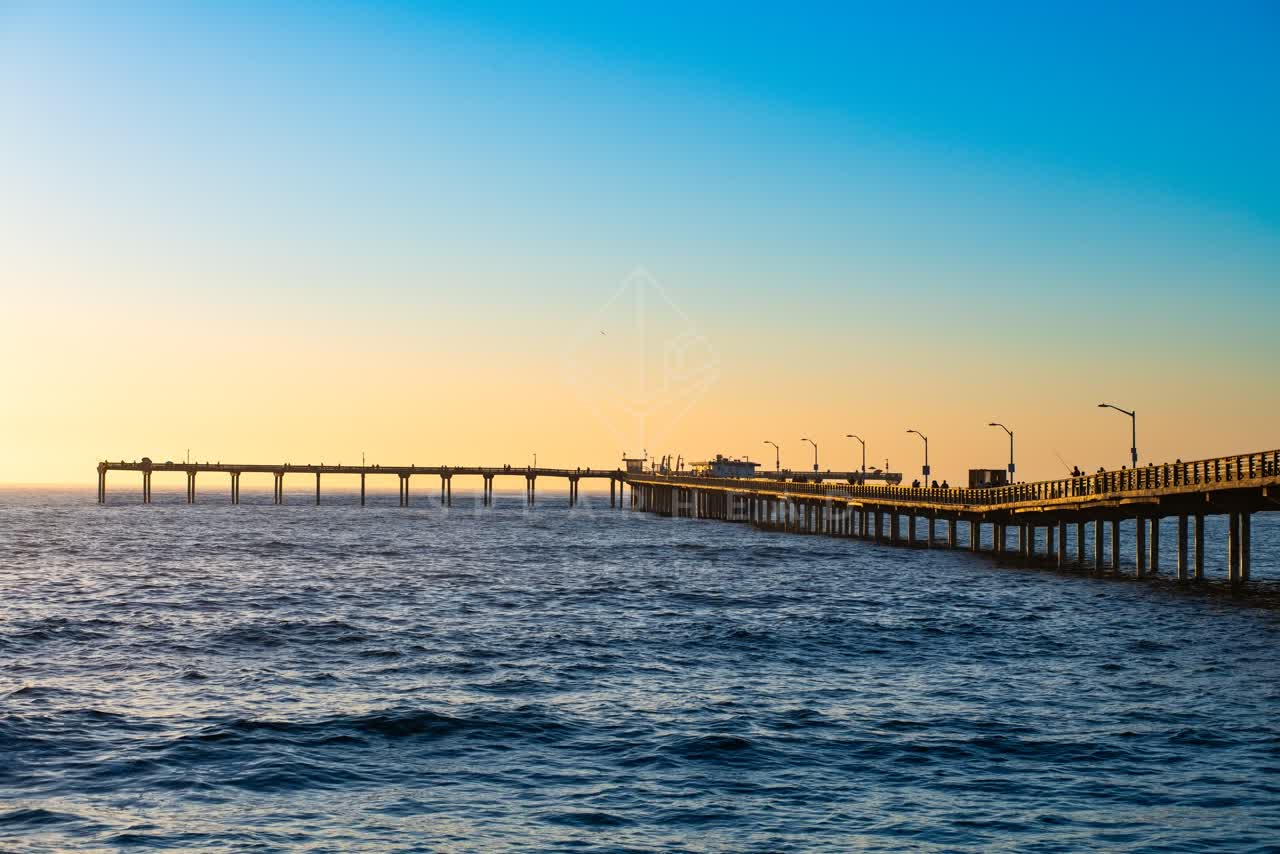 View from the water of the beach, the pier and the ocean in Ocean Beach, with people walking.