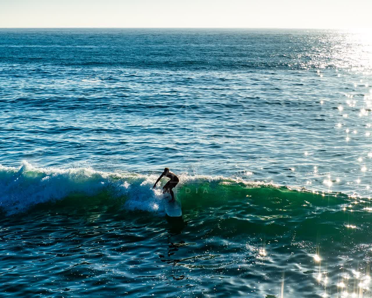 Low aerial view of the beach, the surf and the ocean in Ocean Beach, with surfers out.