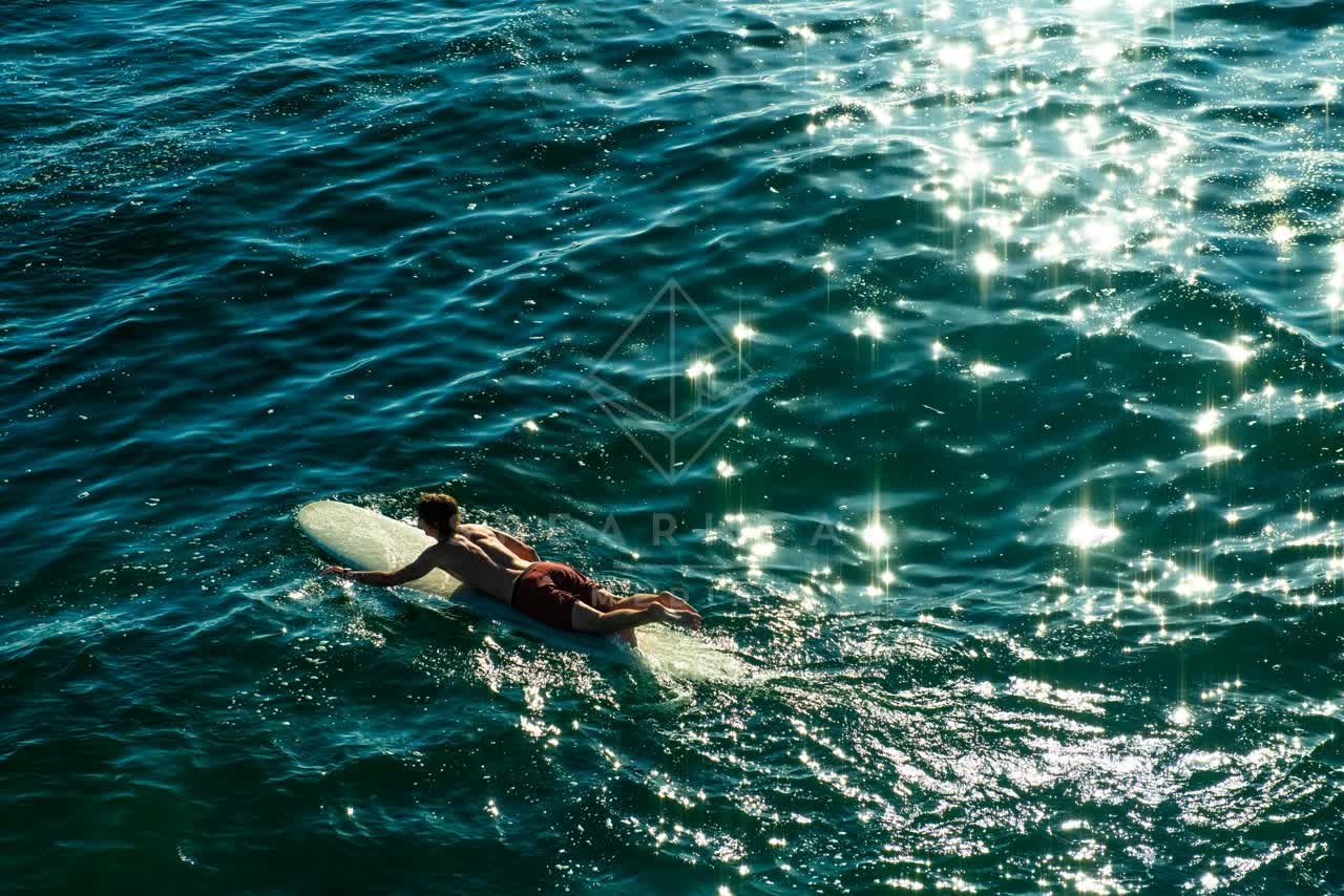 Low aerial view of the beach, the surf and the ocean in Ocean Beach, with paddlers on the water.
