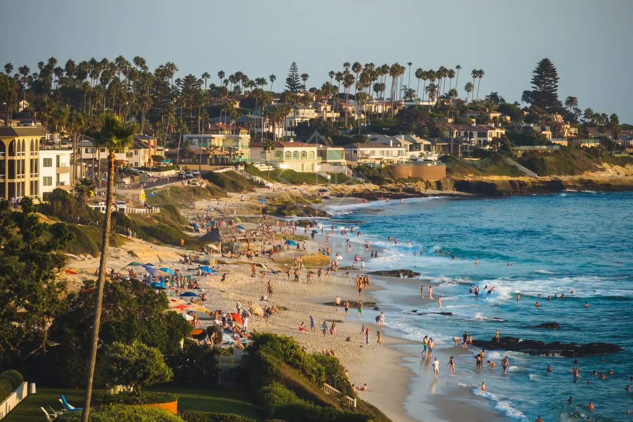 Elevated view of the beach, the surf and palm trees at Windansea, with a crowd gathered.