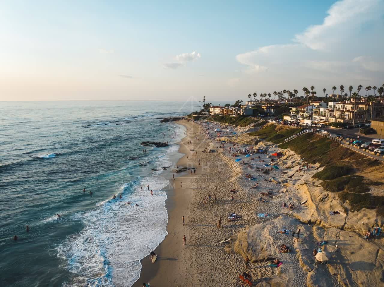 Aerial view of the beach, the surf and palm trees at Windansea, with people walking.