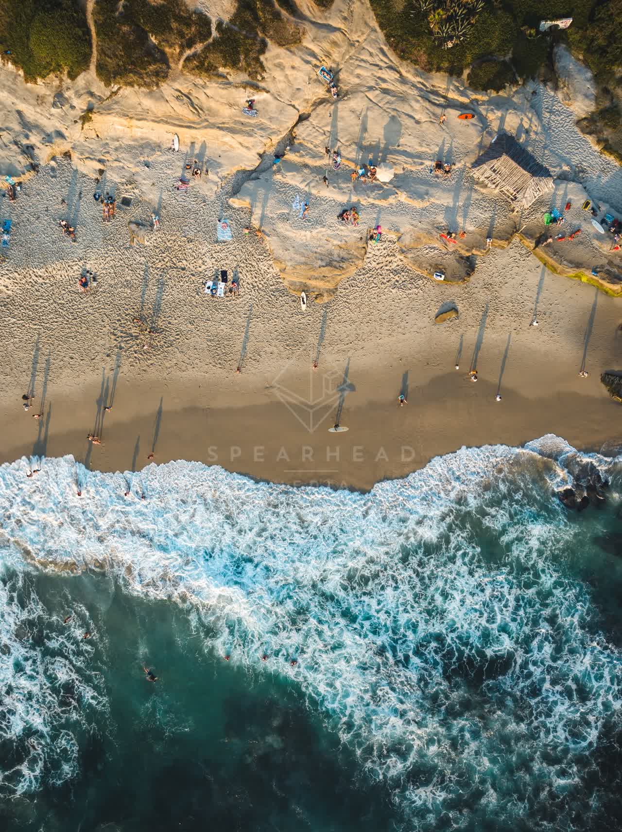 Aerial view of the beach, the surf and the ocean at Windansea, with a crowd gathered.