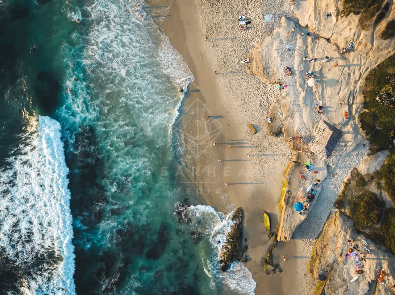Aerial view of the beach, the surf and the ocean at Windansea, with people walking.