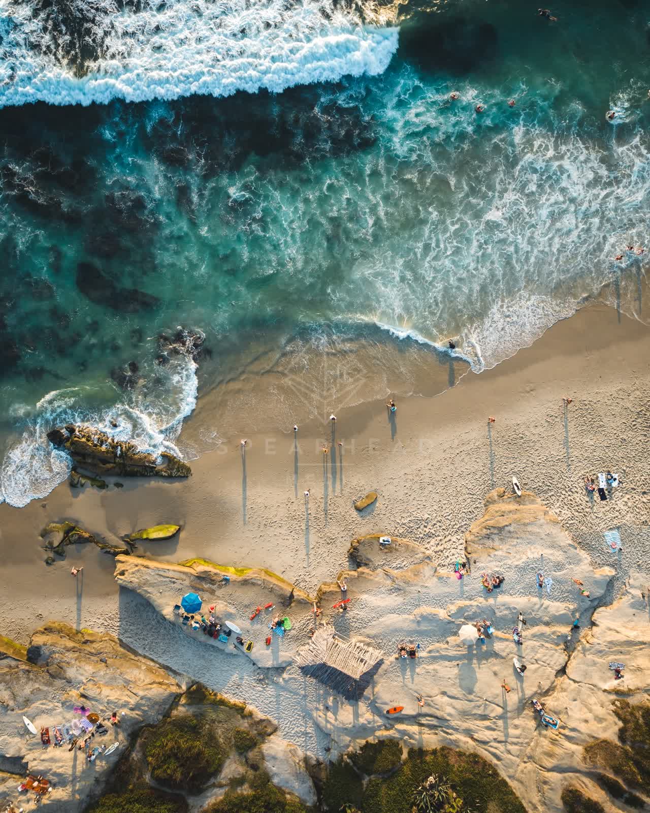 Aerial view of the beach, the surf and the ocean at Windansea, with a crowd gathered.