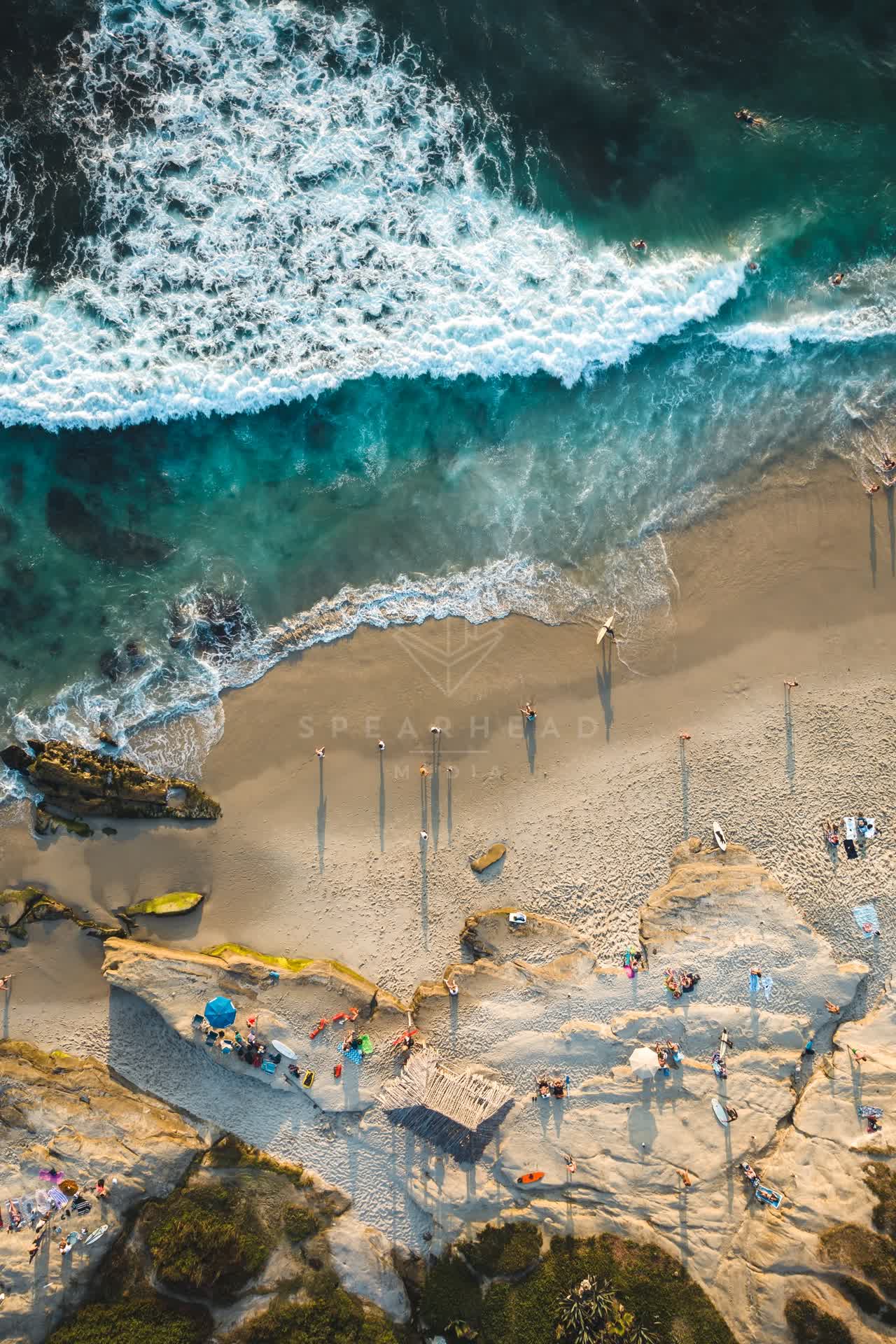 Aerial view of the beach, the surf and the ocean at Windansea, with swimmers in the water.
