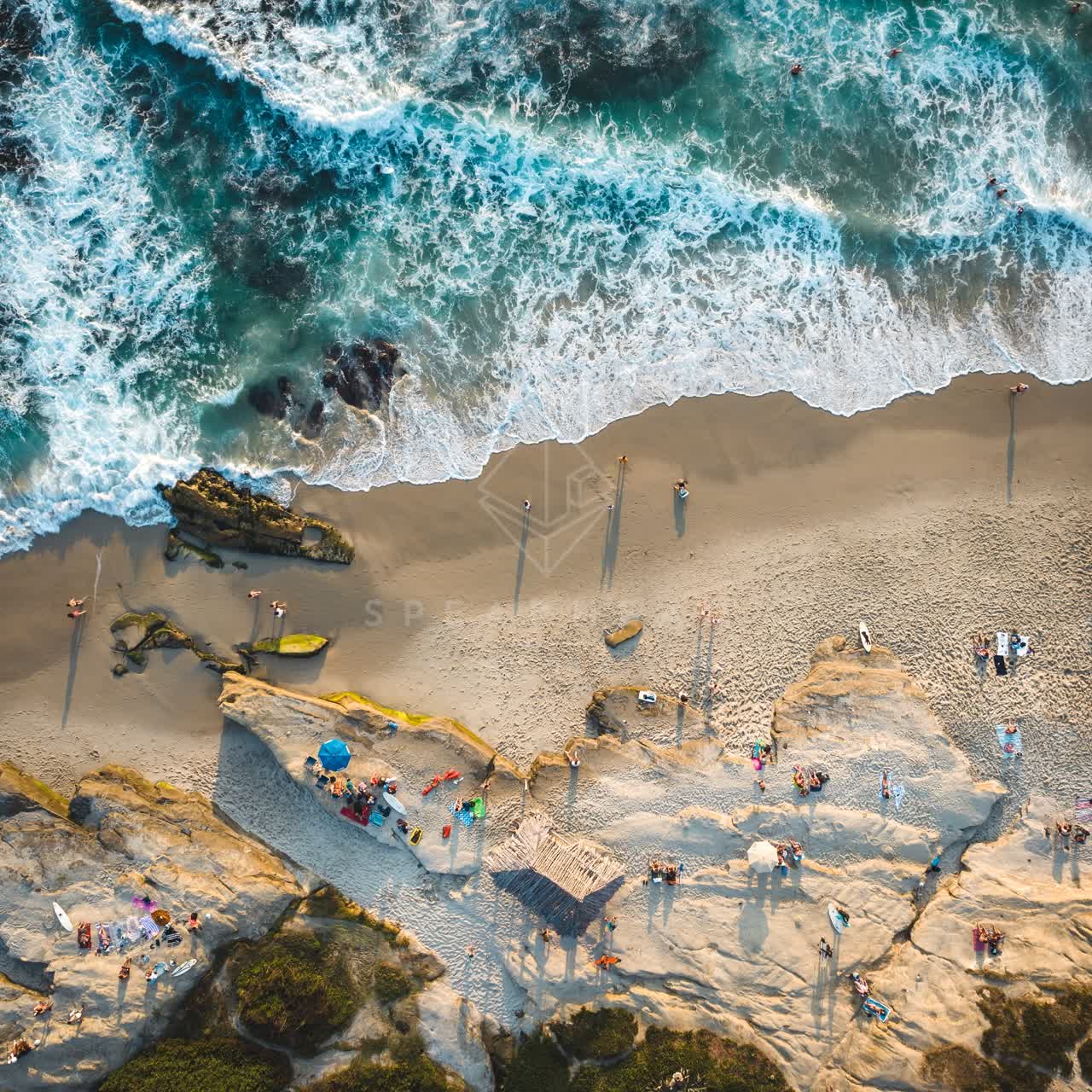 Aerial view of the beach, the surf and the ocean at Windansea, with a crowd gathered.
