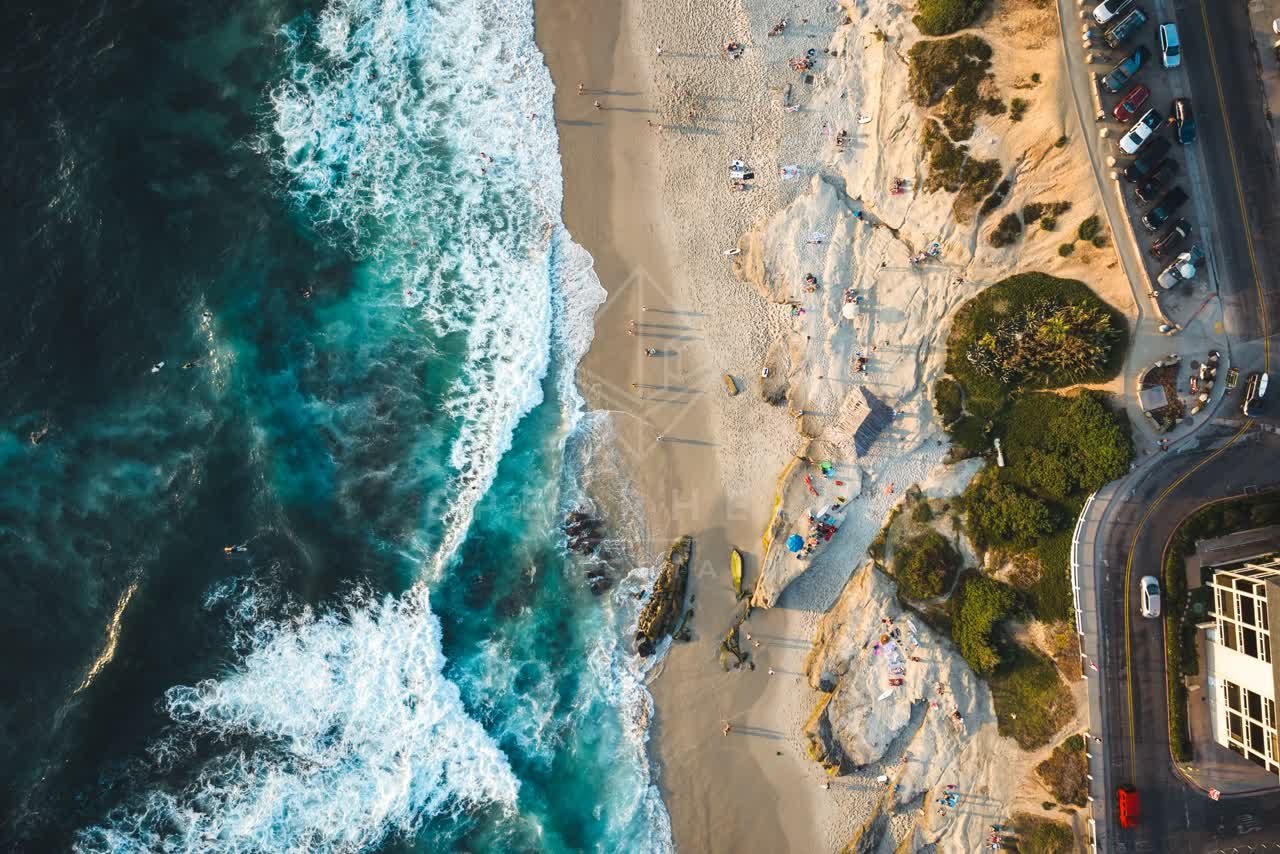 Aerial view of the beach, the surf and the ocean at Windansea, with people walking.