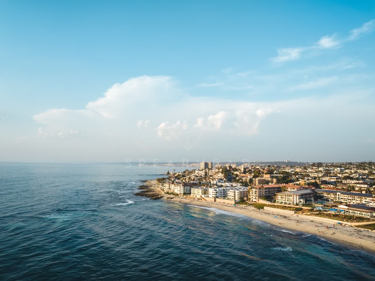 Aerial view of the beach, the ocean and homes at Windansea, with people walking.