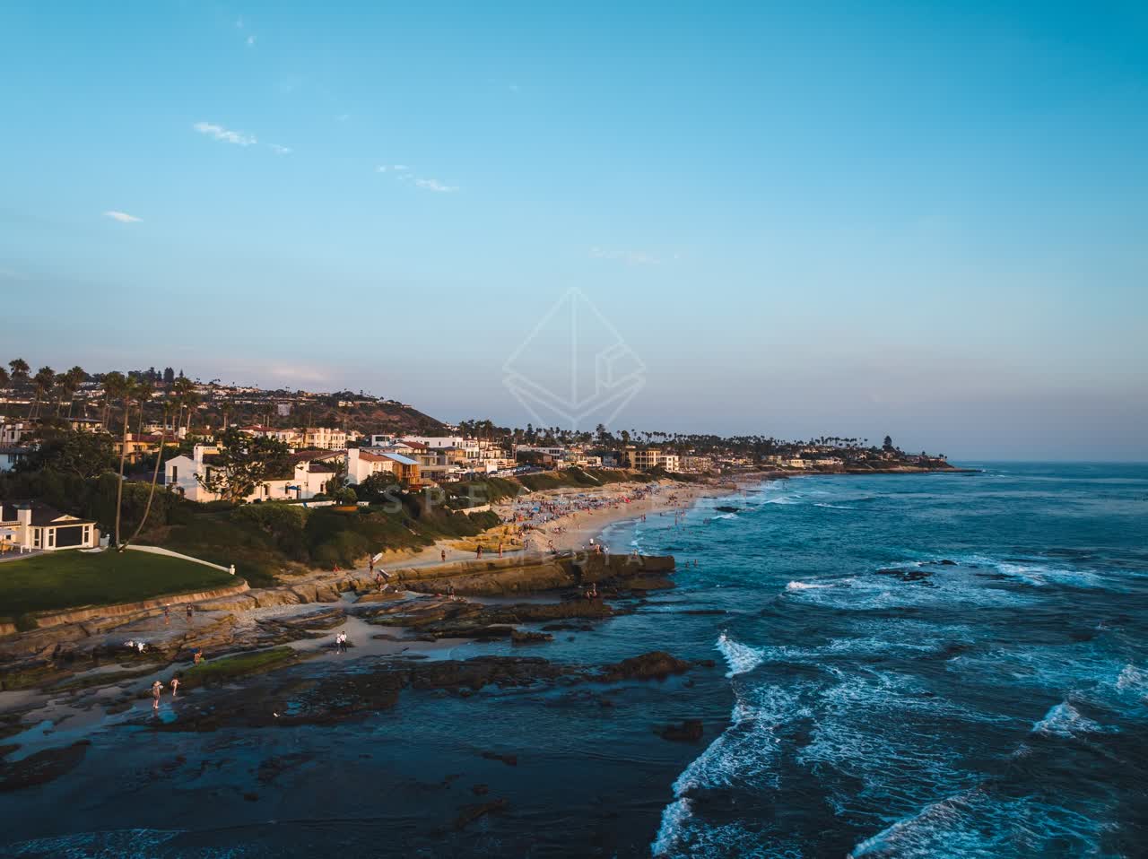 Aerial view of the cliffs, palm trees and the ocean at Windansea, with people walking.