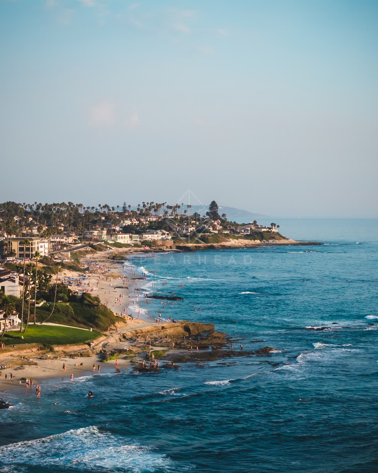 Aerial view of the beach, the surf and palm trees at Windansea, with people walking.
