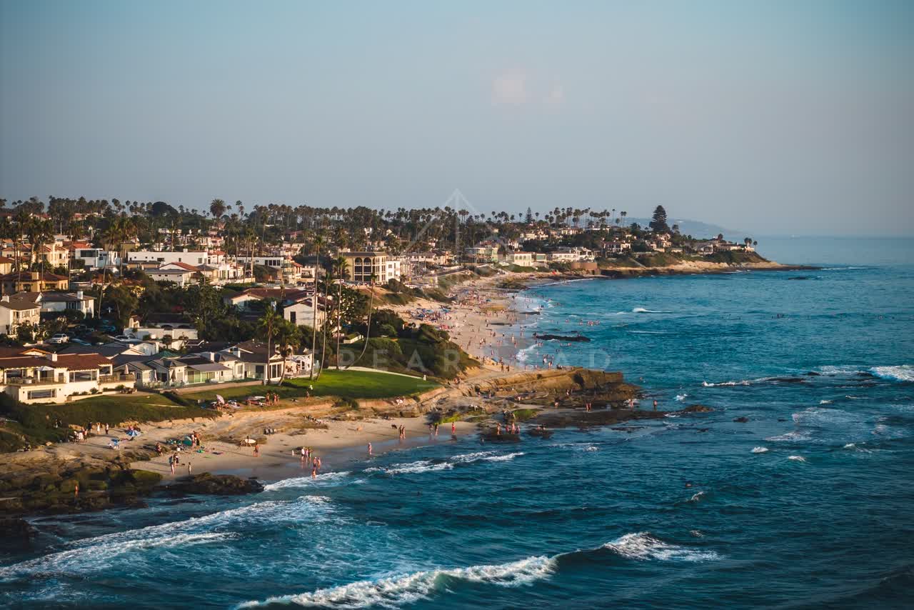 Aerial view of the beach, the surf and palm trees at Windansea, with people walking.