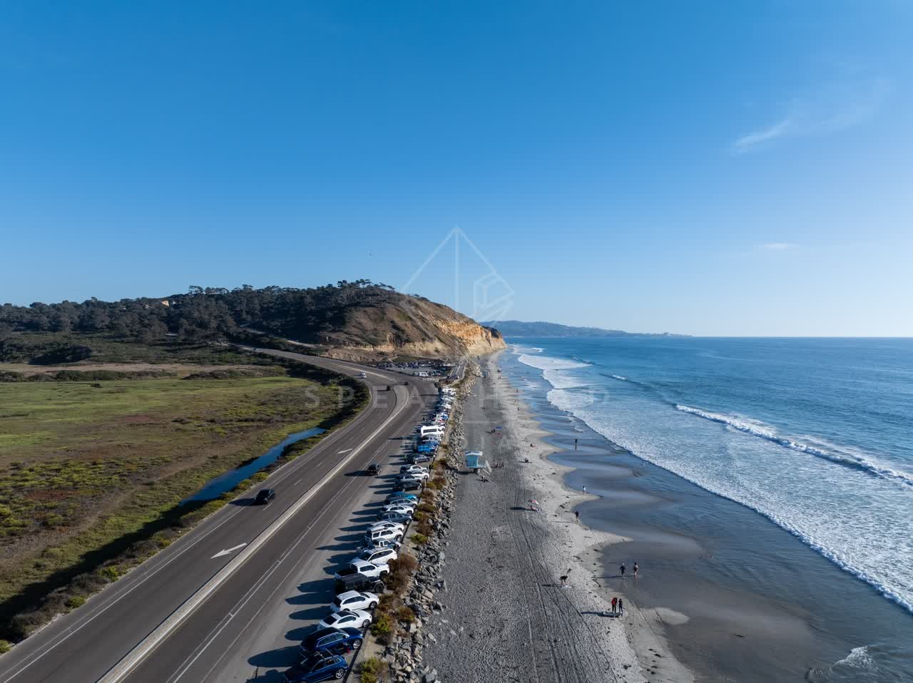 Aerial view of the beach, the surf and the ocean at Torrey Pines, with people walking.