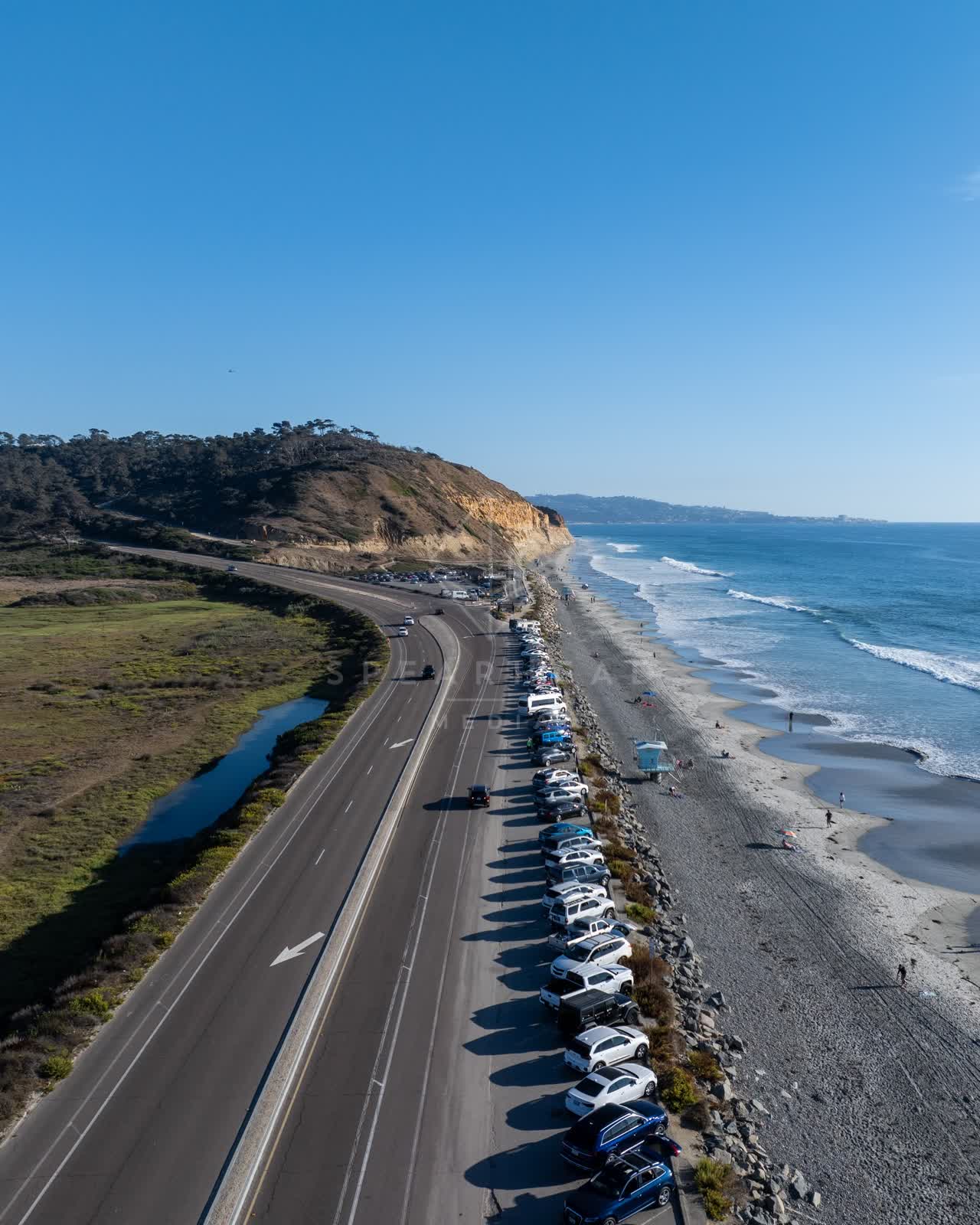 Aerial view of the cliffs, the ocean and the beach at Torrey Pines, with people walking.
