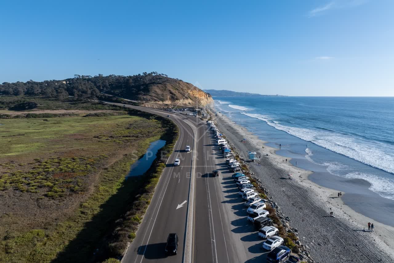 Aerial view of the beach, the surf and the ocean at Torrey Pines, with people walking.