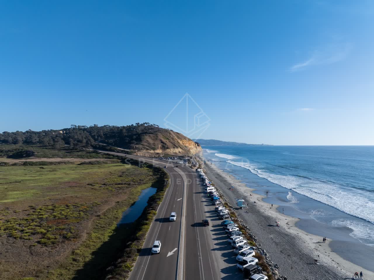 Aerial view of the beach, the surf and the ocean at Torrey Pines, with people walking.