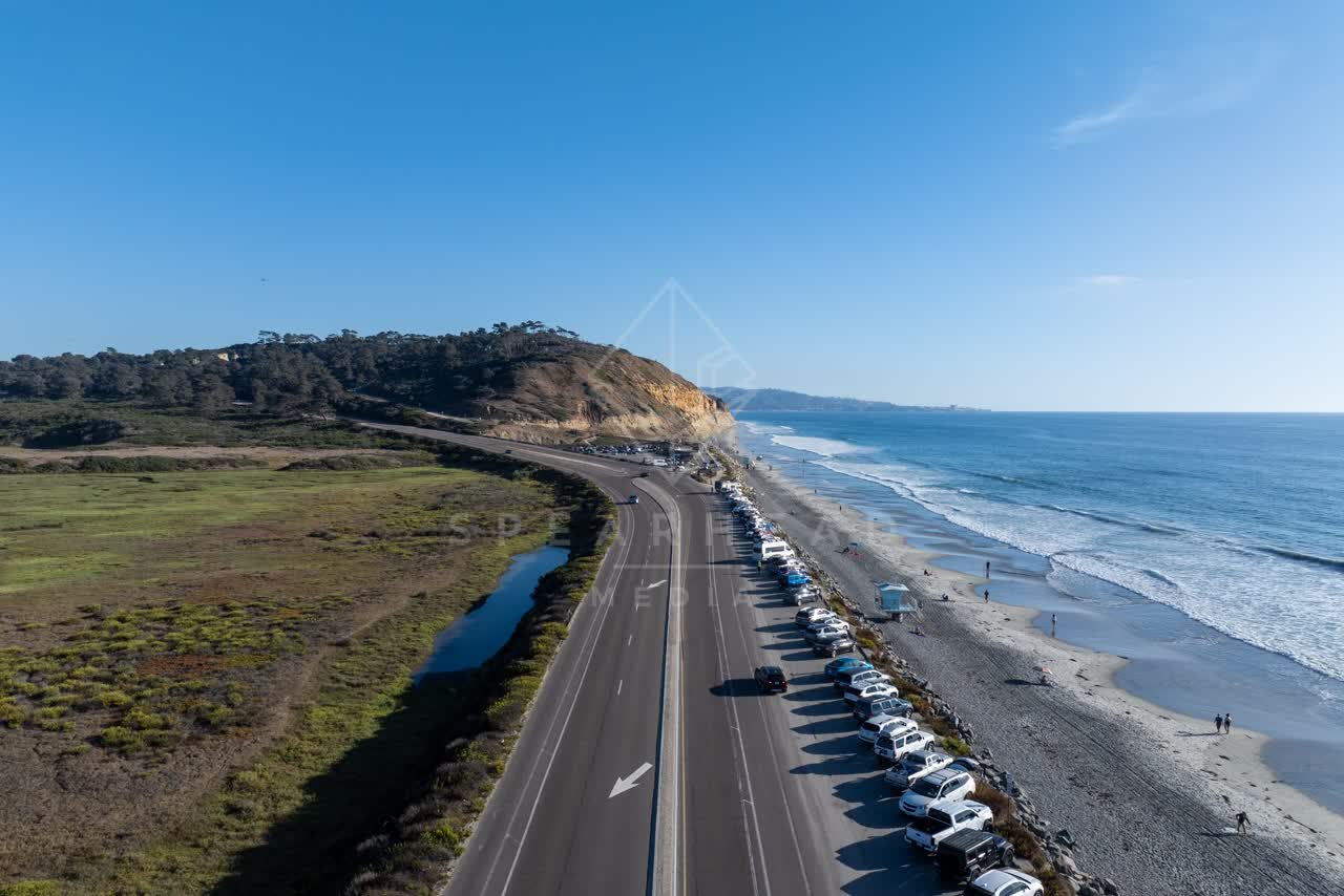Aerial view of the beach, the surf and the ocean at Torrey Pines, with people walking.
