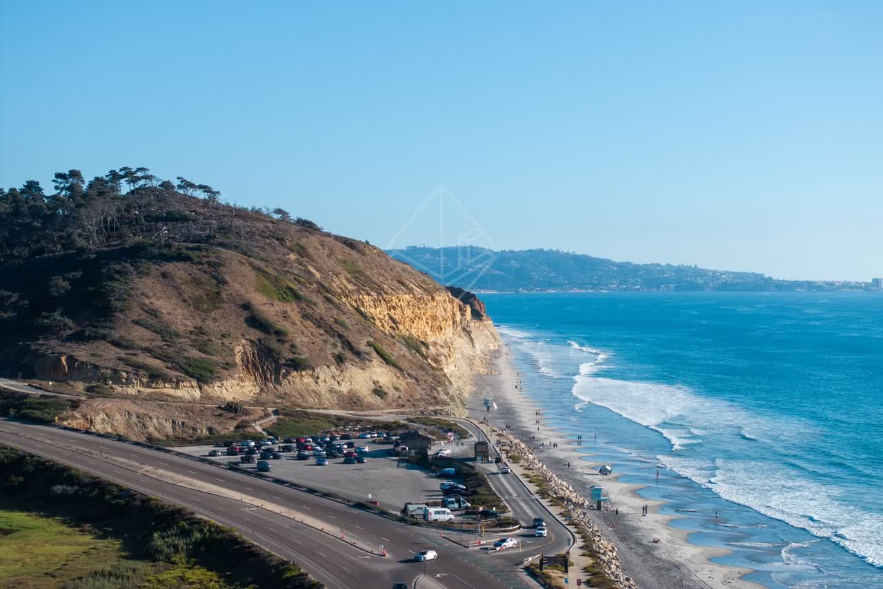 Aerial view of the cliffs, the surf and the ocean at Torrey Pines, with people walking.