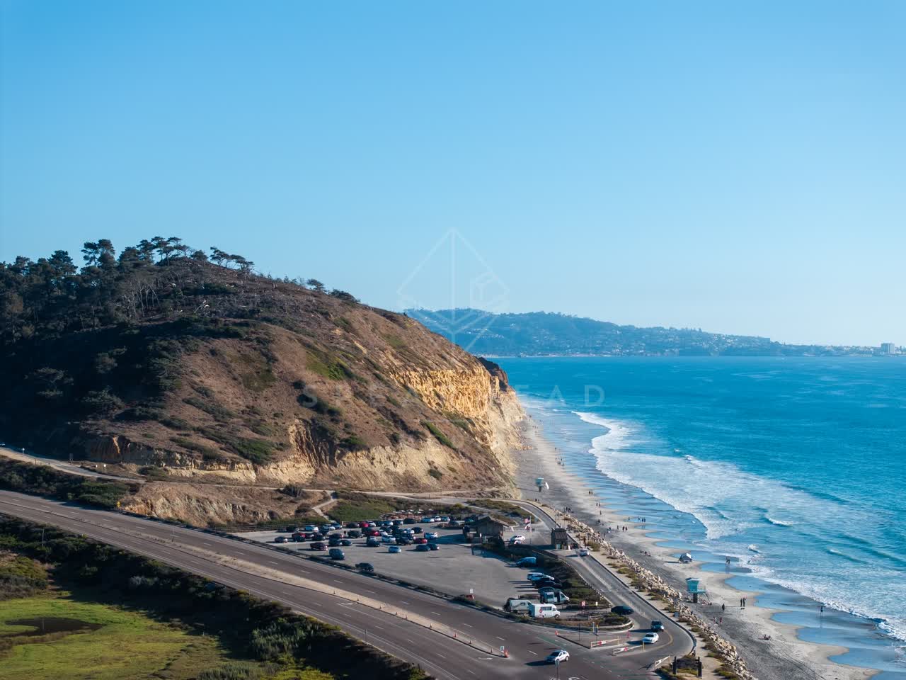 Aerial view of the cliffs, the surf and the ocean at Torrey Pines, with people walking.