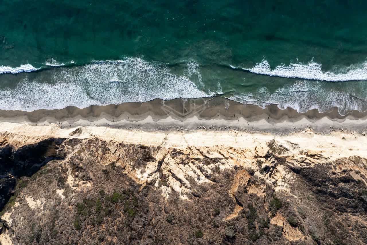 Aerial view of the cliffs, the surf and the ocean at Torrey Pines, with people walking.