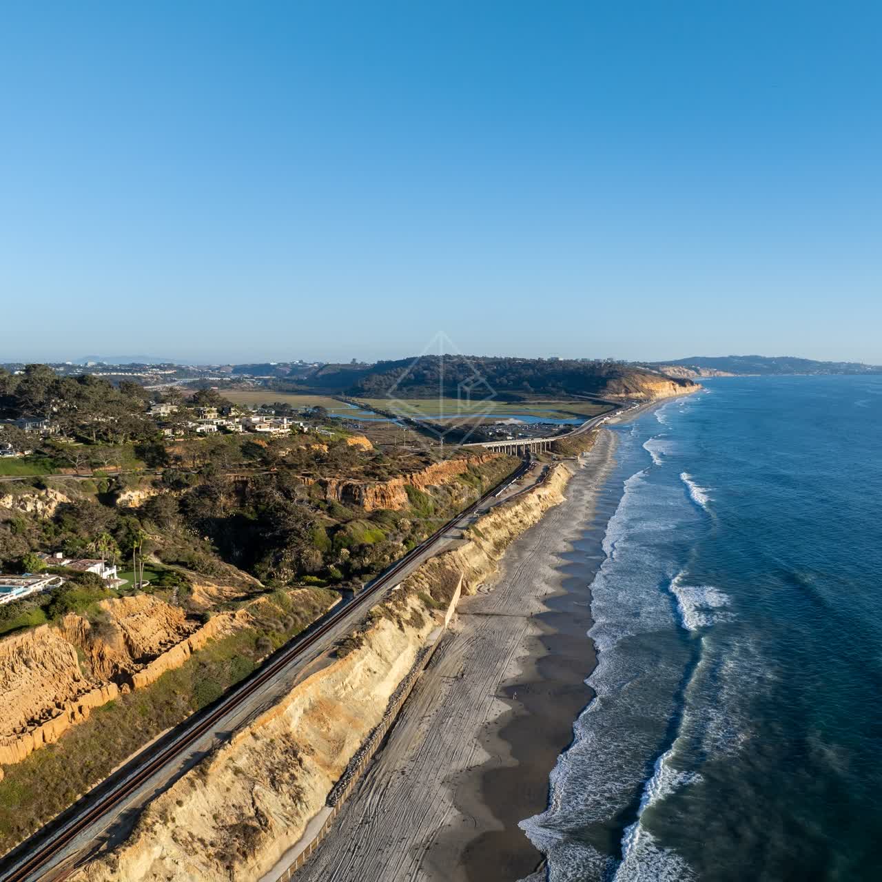 Aerial view of the cliffs, the surf and palm trees in Del Mar.
