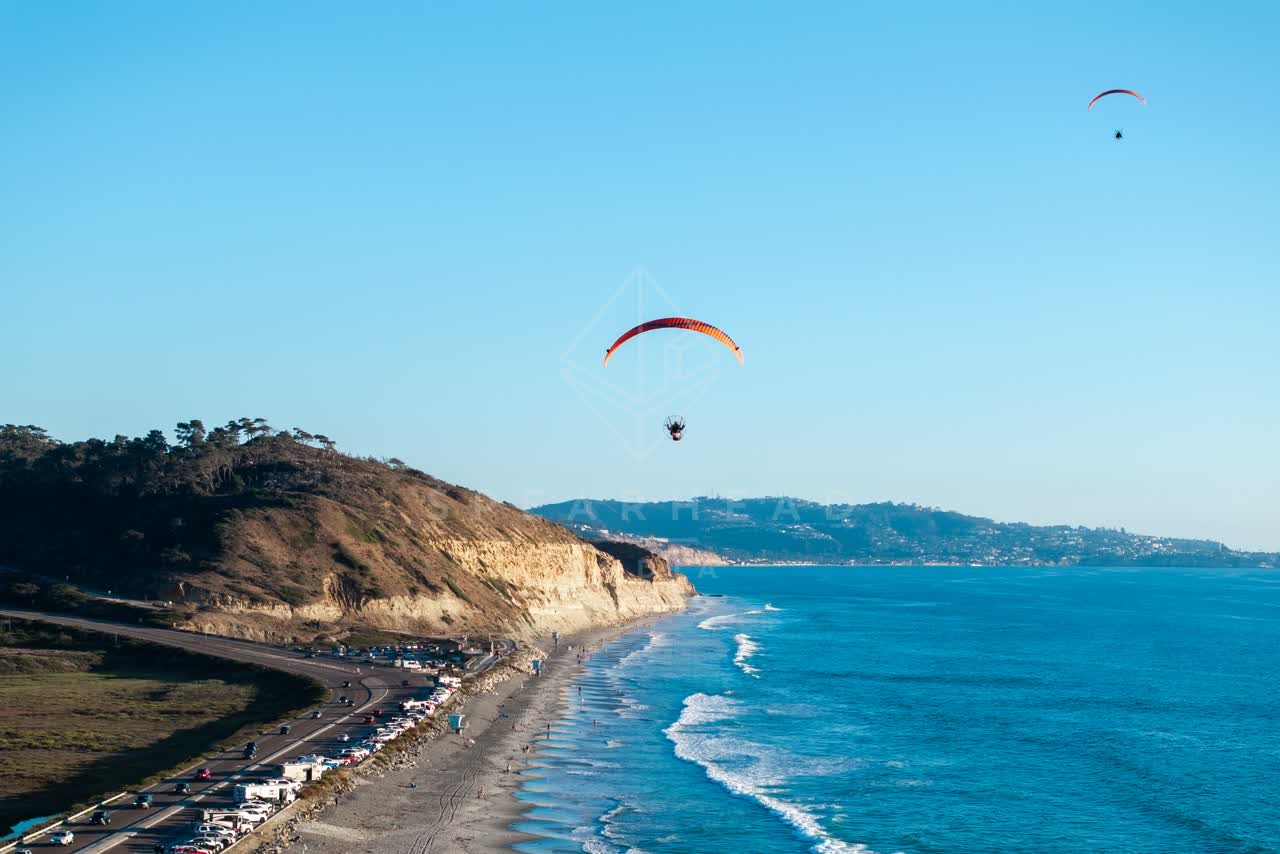 Aerial view of the cliffs, the ocean and the beach at Torrey Pines, with a crowd gathered.