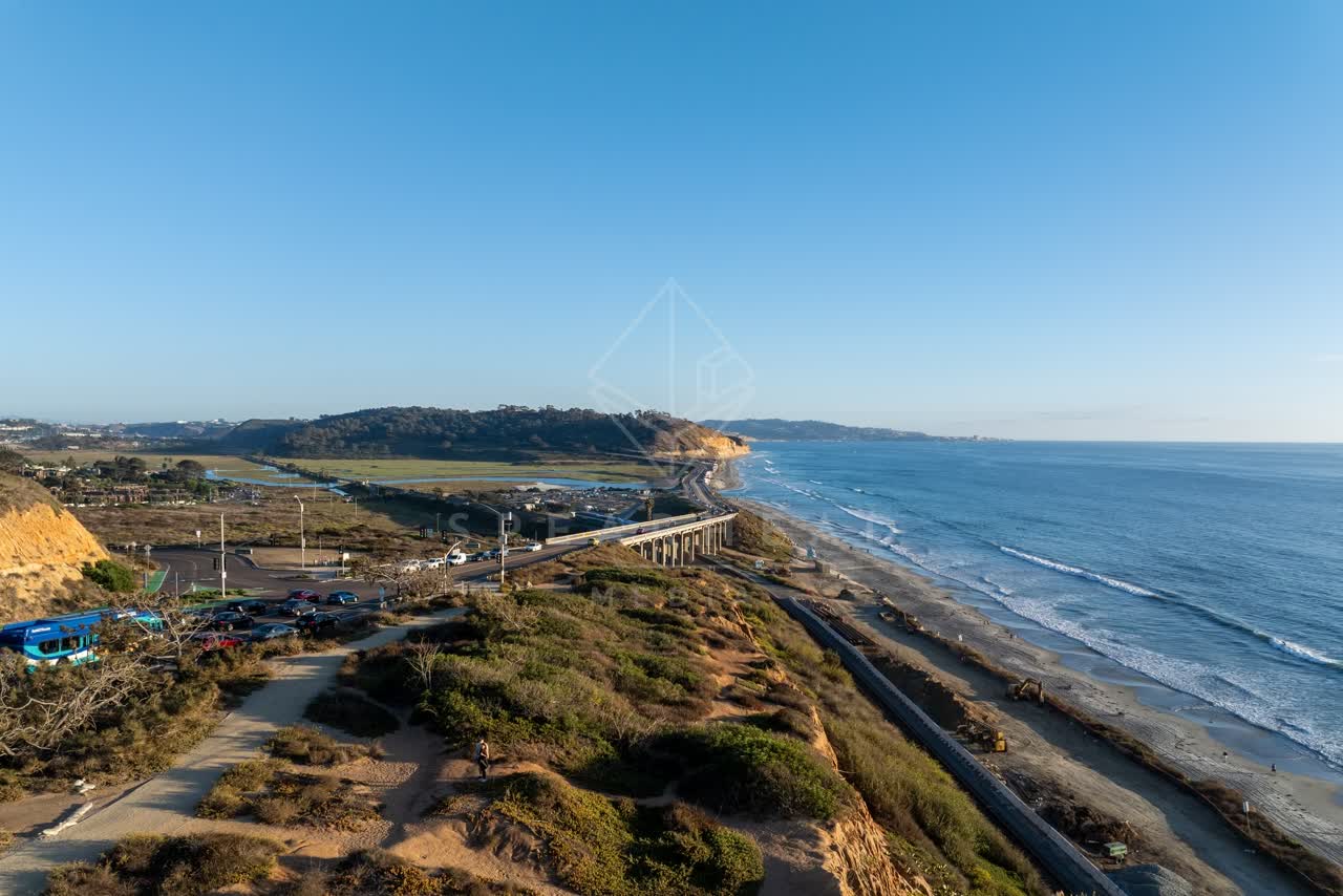 Aerial view of the cliffs, the surf and the ocean in Del Mar, with people walking.