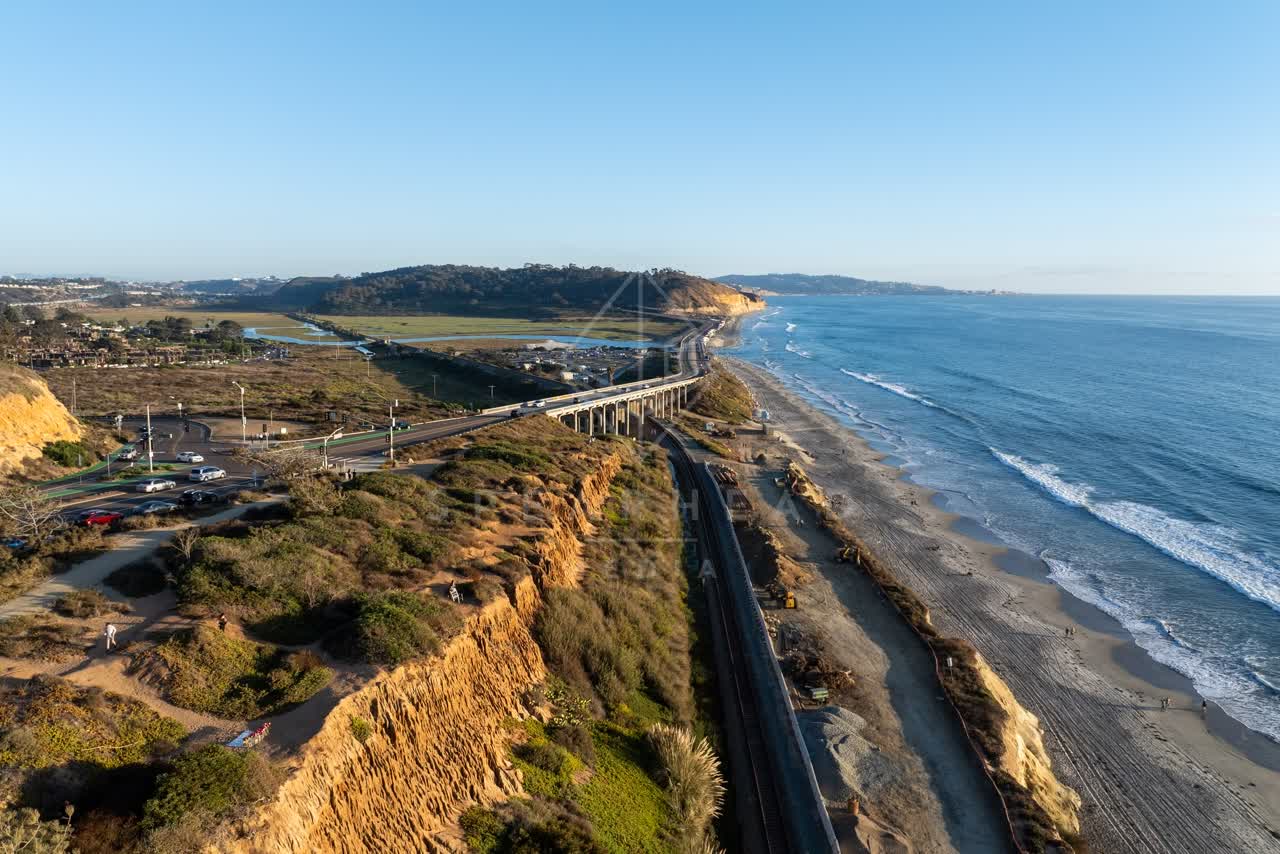 Aerial view of the cliffs, the ocean and the beach in Del Mar, with people walking.
