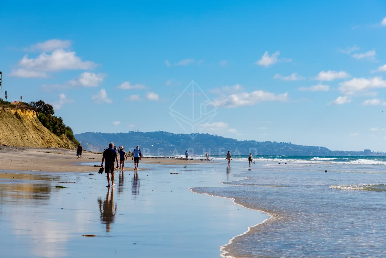 The beach, the surf and the ocean at Powerhouse Park, with people walking.
