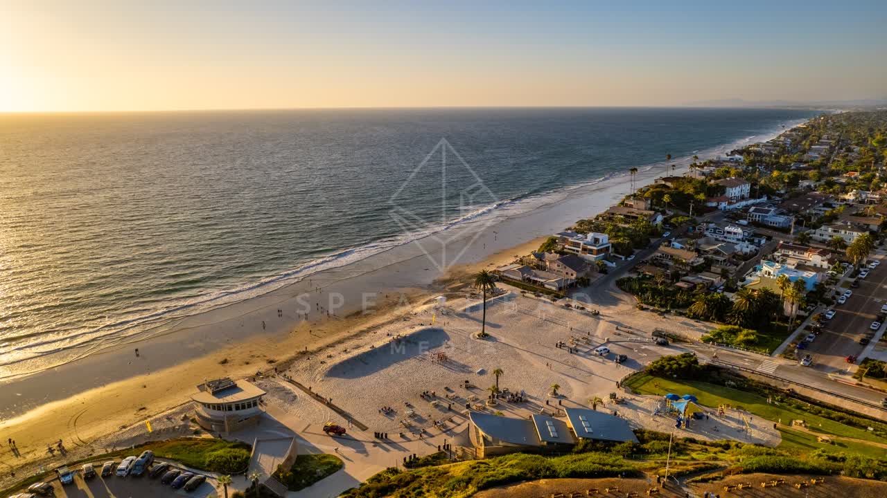 Aerial view of the beach, palm trees and the ocean at Moonlight Beach, with people walking.